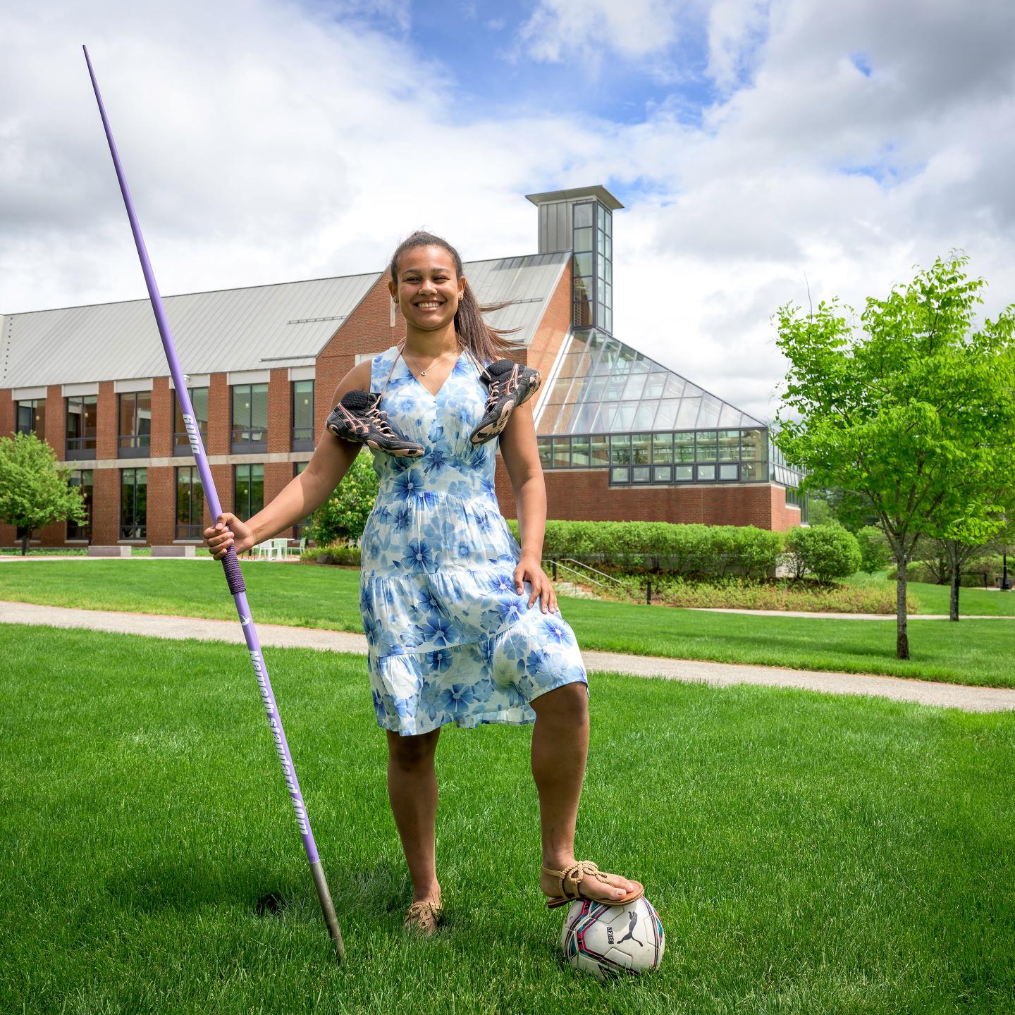 Cami Capdevila posing in front of Lindsay Center with javelin and soccer ball