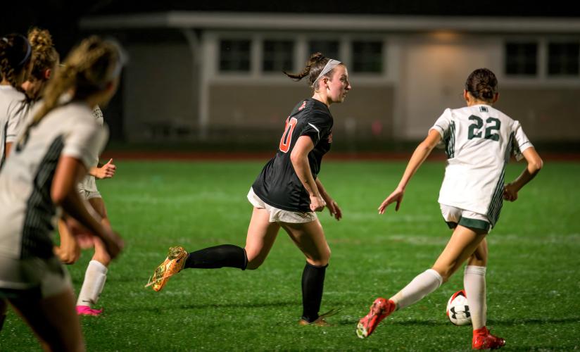 Georgia Bussey '24 takes the ball up the field in SPS Girls Varsity Soccer's game against Deerfield Academy during a special home night game in October, 2023.