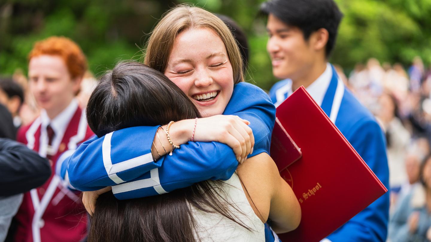 Two graduates hugging at conclusion of Graduation Ceremony