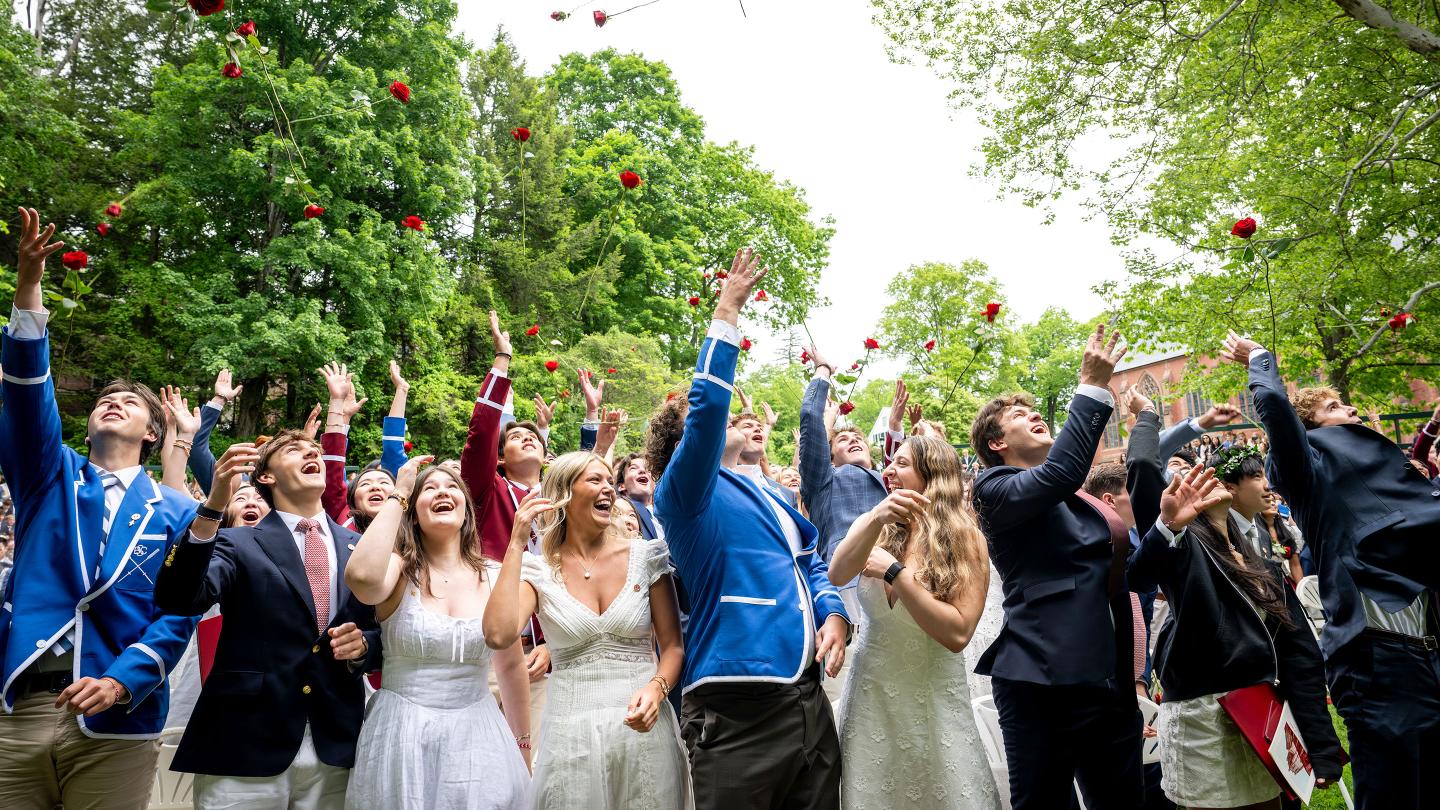 Graduates toss their roses in the air at the conclusion of the Graduation Ceremony